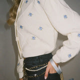 Cardigan corto in maglia con bottoni a rombo e ricami floreali a girocollo